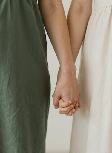 Close-up of parents holding a toddler's hand. Serene and heartfelt elegance, modern minimalism. Warm intimate storytelling. Earthy tones highlighting dark green (#2A362B), muted green (#5F705B), warm beige (#C7B7A3), and off-white (#F7F3EE).