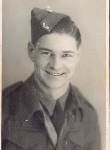 Vintage black and white portrait of a smiling young soldier in a military uniform and forage cap.
