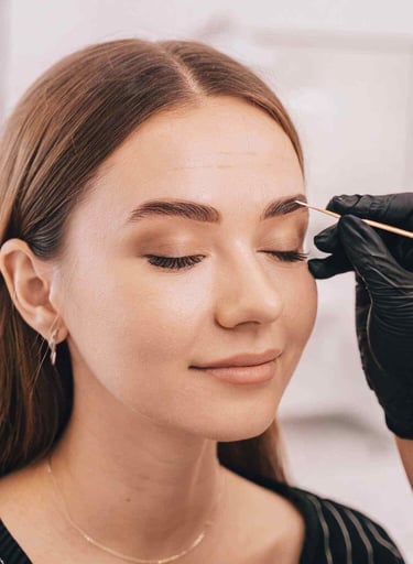 a woman is getting her eyebrows done by a professional makeup artist