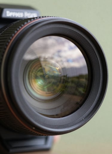 Close-up of a professional camera lens reflecting a South American / Brazilian landscape, with soft Pearl White bokeh highlights and a Pale Sage Green background, emphasizing artistic precision.