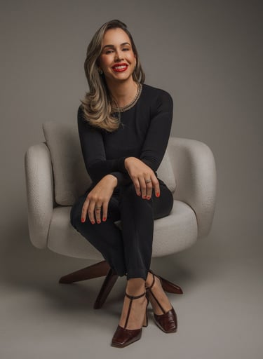 Professional woman in elegant black attire sitting in a modern chair for a corporate studio portrait.