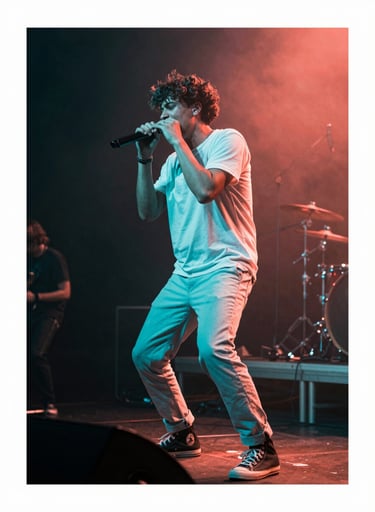 A dynamic shot of a musician performing live on a stage in a International / English-speaking music venue. The lighting is funky and vibrant with bright turquoise and vibrant coral hues. The artist is captured in a moment of peak energy, surrounded by dark charcoal shadows.