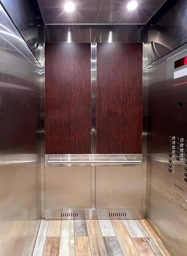 elevator interior with deep red wood wall panels, round handrails and a warm tile floor