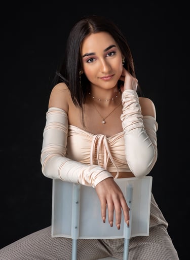 a woman in a beige top and pants sitting on a chair. estudio, quinceañera, retrato, asturias
