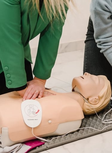 Two women administering CPR training on a CPR dummy in a training