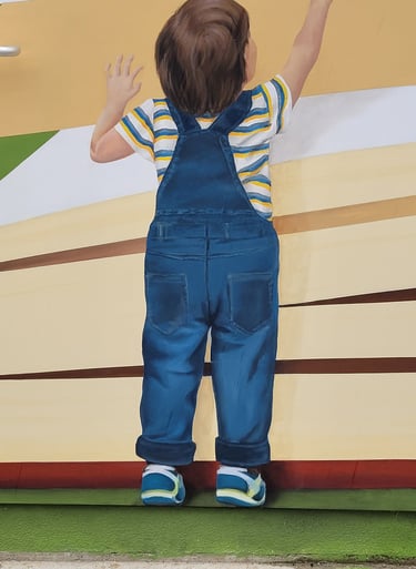 Fresque sur façade. Un garçon debout tourne les pages d'un grand livre.