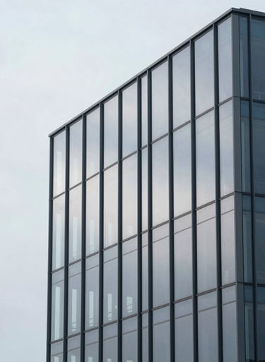 A minimalist architectural shot of a modern glass building reflecting a soft mist white sky, clean and professional composition.