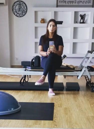 Pilates instructor Maalini sitting in the studio taking a relaxed selfie at The Pilates Room Bangsar