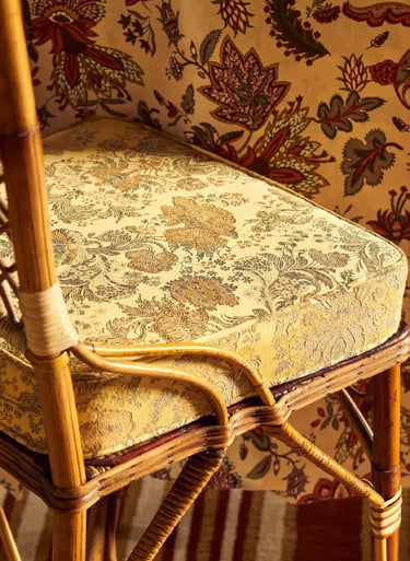 Chaise avec un coussin recouvert d'un coussin au tissu jaune et floral