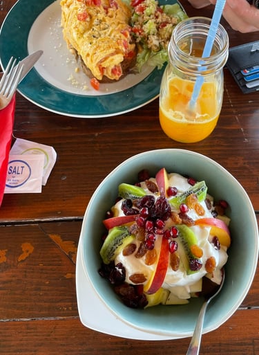 a bowl of fruit salad with a glass of orange juice
