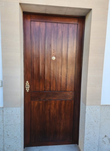 Traditional dark walnut stained wood front door with vertical panels and brass hardware.