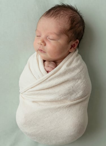 A newborn baby wrapped in a soft cream linen cloth, cinematic side lighting, peaceful and warm atmosphere with #E2D7C3 palette.