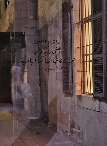 Arabic calligraphy on a glass wall reflecting stone building with shutters luminous spac