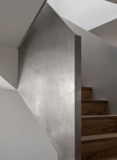 A close-up of a modern staircase made of polished steel and dark oak, featuring precise joinery and sophisticated lighting, using the #2F2E2E and #D9D2C7 color palette.