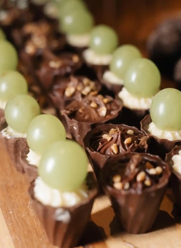 Imagem de deliciosos doces decorados com uvas verdes e cobertura de chocolate, perfeitos para festas