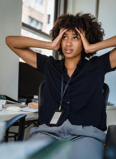 Une jeune femme noire aux cheveux crépus qui se tient la tête entre les mains