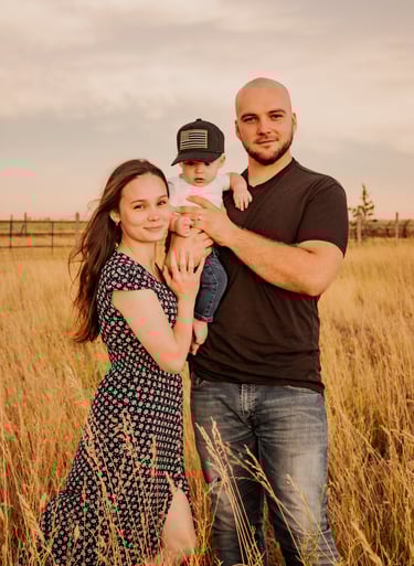 a man and woman standing in a field holding a baby