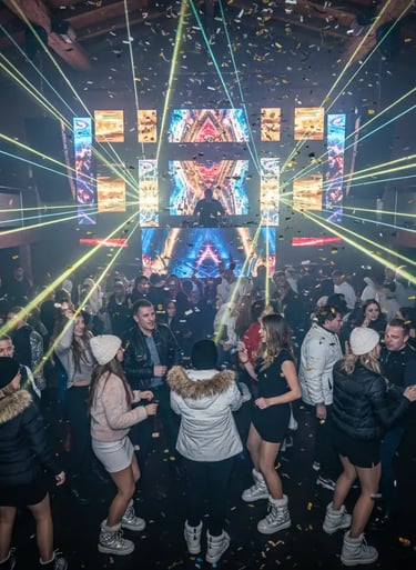 High-energy crowd dancing in an upscale Ischgl nightclub with vibrant laser lights and falling confe