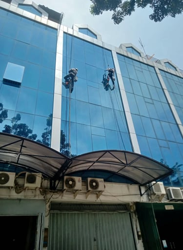 a man is cleaning a building with a window cleaner