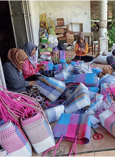 Artisans shaping and adjusting handmade plastic woven bags during production at Craftvitas Indonesia.