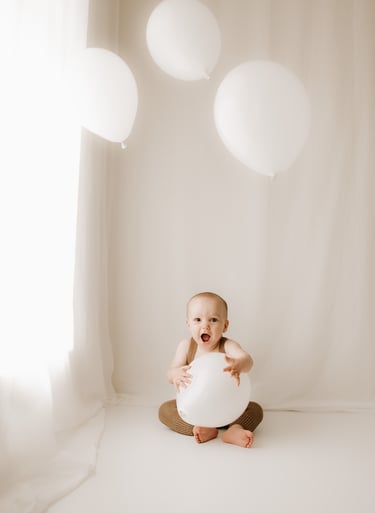baby holding balloons for a cake smash photo session in Littlehampton studio