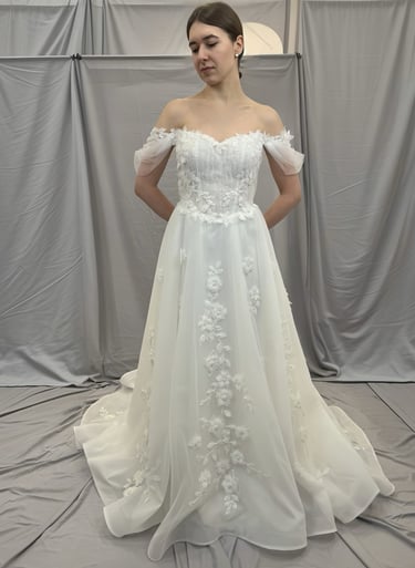 a woman in a wedding dress standing in front of a white backdrop