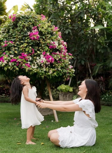 Two sisters playing together in a tropical garden during a relaxed family photography session at a private villa in Seminyak
