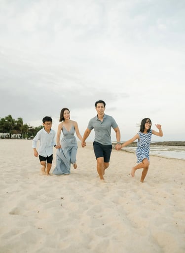 Family running together along the beach during a luxury family photography session at The Ritz-Carlton Bali.