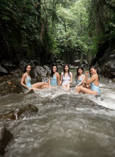 Group portrait of women sitting in river surrounded by jungle at Kanto Lampo Waterfall Bali