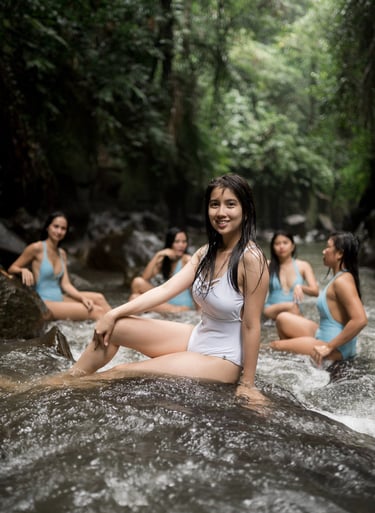 Friends portrait sitting together in shallow river at Kanto Lampo Waterfall Bali