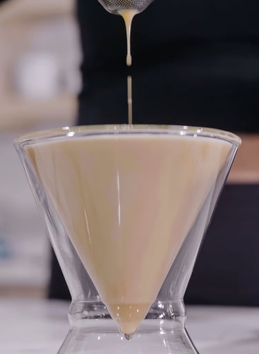 a person pouring a liquid into a glass bowl