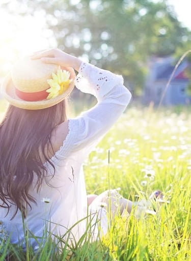 a woman in a hat sitting in a field