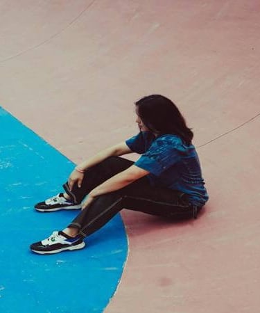 Person sitting alone in quiet reflection, expressing struggle, loneliness, or contemplation