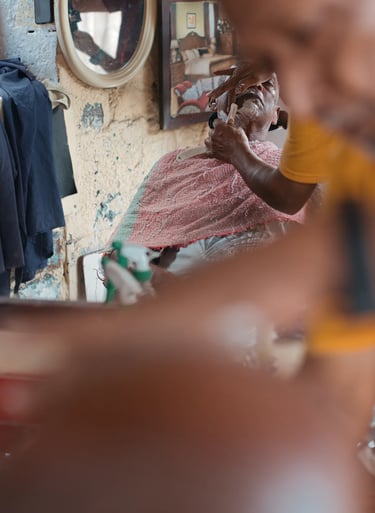 Barber giving a shave reflected in mirror, Royal Road Mahebourg, Mauritius