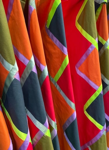 Vibrant geometric patchwork fabric with colorful diamond patterns and ribbon trim detailing.