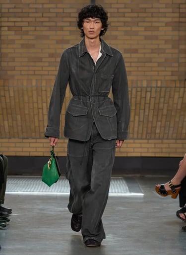 Calvin Klein Spring Summer 2026 runway look featuring grey utilitarian suit with green handbag.