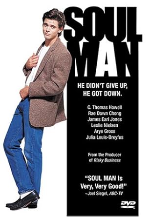 a man in a suit and jeans standing in front of a poster