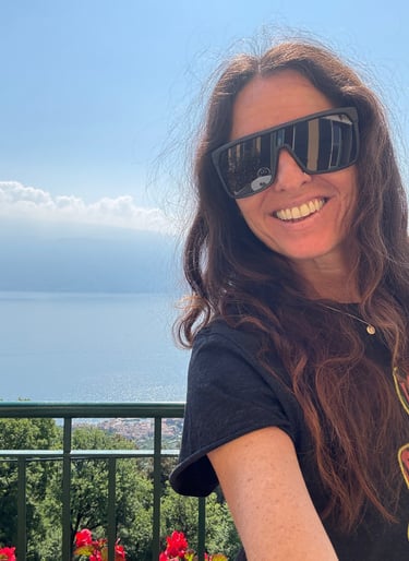 Michael Alexa Pitts smiling in the sunny, blue sky day on a mountainside with Lake Garda, Italy down below in the background
