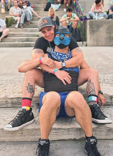 Two men, one wearing a pup mask, pose together.