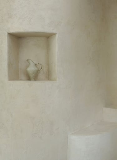 Plastered wall with an architectural niche and a handcrafted pot.