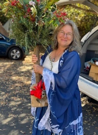 smiling lady in blue and white holding a holiday tree decoration