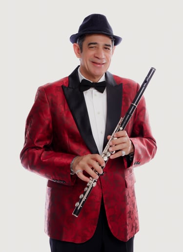 Maestro Bobby Ramiez in a tuxedo suit and hat with a flute