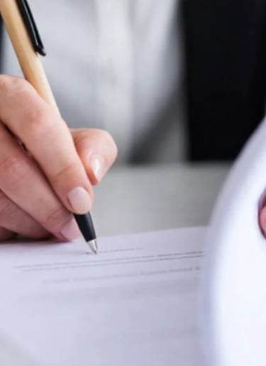 A business professional signing a legal contract with a pen on a desk.