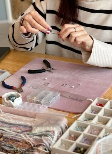 Artesana de joyería utilizando pinzas para ensamblar aretes de cuentas hechos a mano