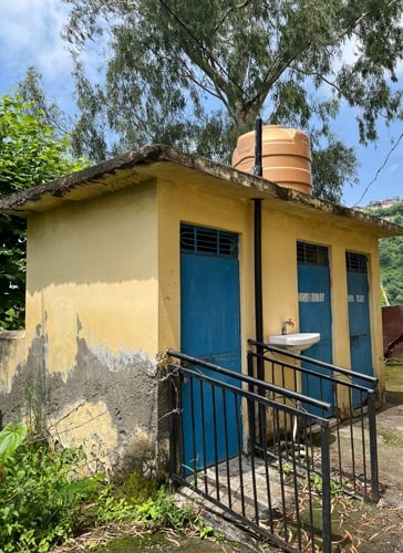 Small yellow toilet block with 3 blue doors.