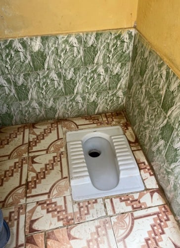 Squat toilet with tiles on floor and walls..