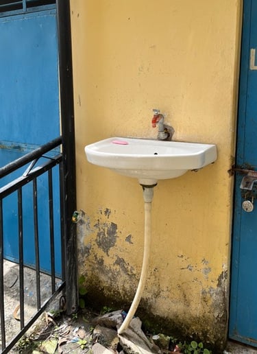 Small basin with single tap on yellow wall.