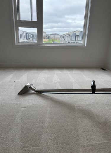 Carpet cleaning wand in use during a deep steam cleaning service on a residential carpeted floor.