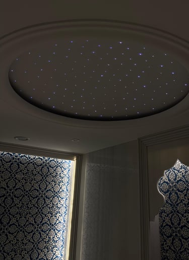 Luxury interior with a circular fiber optic star ceiling and blue patterned Arabic wall art.