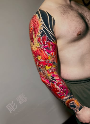 Tatuaggio sul braccio di un drago giapponese rosso e giallo eseguito da Horidoku 